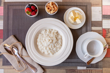 Healthy breakfast. Rice porridge bowl with berries and nuts on the table, hot and healthy breakfast food, top view