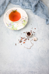 Royal Albert Iris Fine Bone China Tea Cup and Saucer with Herbal Tea and Tea Infuser on Blue Background
