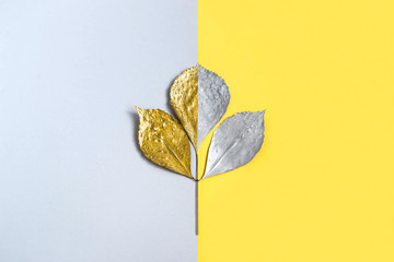 Silver and gold branch with leaves on two-color background
