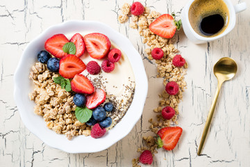 Granola with berries, yoghurt and coffee for breakfast. Cereal oats with strawberries, blueberries and raspberries for healthy eating. Top view
