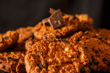 Chocolate chip cookies on rustic dark black background. Stacked chocolate chip cookies on brown napkin. Symbolic image with place for text. Freshly baked. Concept for a tasty snack. Sweet dessert