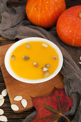 Bowl of pumpkin soup on rustic wooden background