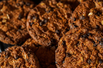 Chocolate chip cookies on rustic dark black background. Stacked chocolate chip cookies on brown napkin. Symbolic image with place for text. Freshly baked. Concept for a tasty snack. Sweet dessert