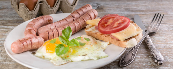 Fried eggs and sausages on a wooden table. Food banner