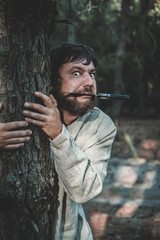 maniac with a knife stands behind a tree