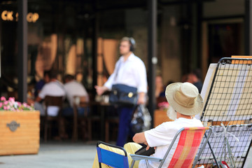 Stary mężczyzna siedzi na fotelu przed restauracją. - obrazy, fototapety, plakaty
