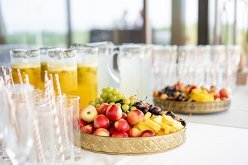Fresh Fruit platter buffet at business or wedding event venue. Self service or all you can eat - cherries, nectarine, grapes and pineapple. Table with cold drink and snacks and tableware