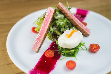 salad of tuna with egg and cherry tomatoes, on a white plate