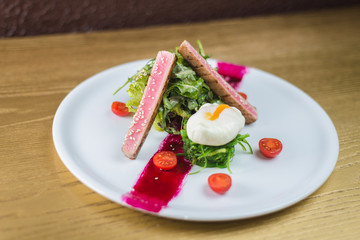 salad of tuna with egg and cherry tomatoes, on a white plate