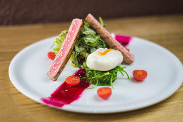 salad of tuna with egg and cherry tomatoes, on a white plate