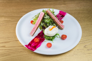 salad of tuna with egg and cherry tomatoes, on a white plate