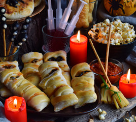 Halloween trick or treat party. Funny delicious food and pumpkin on wooden background - mini pizza,...