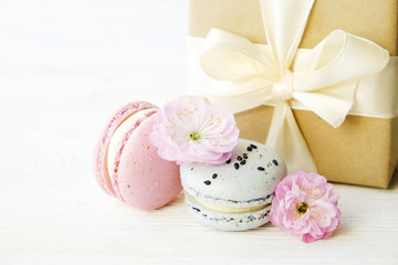 Blueberry and strawberry flavored french macaron desert cakes, present box wrapped in brown craft paper, tied with silk yellow bow, spring flowering. Isolated background, close up, copy space.