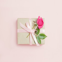 Gift box with rose on pink bacground.