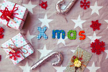 Handmade wraped modern gift box on fabric with stars. Christmas flat lay background. Xmas word from colorful letters.