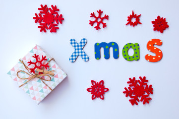 Christmas card with gift box, word xmas and red snowflakes on white background.