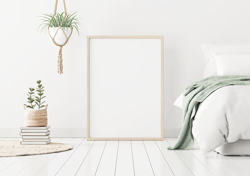 Poster mockup with wooden vertical frame standing on floor in bedroom interior with bed, green plaid and plants on white wall. 3D rendering.