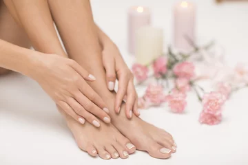 Wall murals Pedicure The picture of ideal done manicure and pedicure. Female hands and legs in the spa spot.