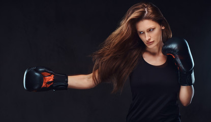 Beautiful brunette female boxer during boxing exercises, focused on a process with serious concentrated facial.