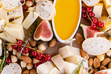 Light Italian snacks. A buffet table at a dinner party. Cheese plate. Delicious cheese mix on wooden table. Tasting dish on a wooden plate. Food for wine.