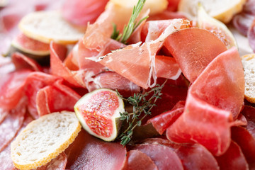 Food tray with delicious salami, pieces of sliced ham, sausage. Cutting sausage and cured meat on a celebratory table.