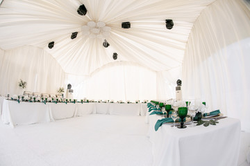 Beautiful banquet hall under a tent for a wedding reception. Interior of a wedding tent decoration...