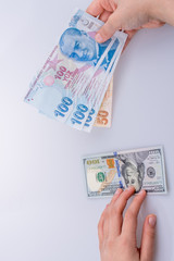 Hands holding American dollar banknotes and Turksh Lira banknotes side by side