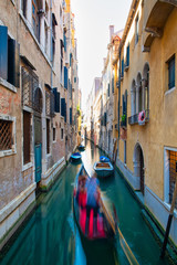 Fototapeta na wymiar Blurred effect for a gondolier with tourists in a canal in Venice