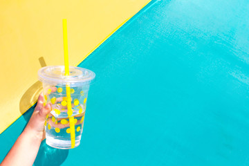 Lemonade drink in a glass on a green and yellow background. Summer concept. Healthy lifestyle.