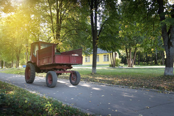 Fototapeta na wymiar Vintage red tractor at the asphalt road with trees