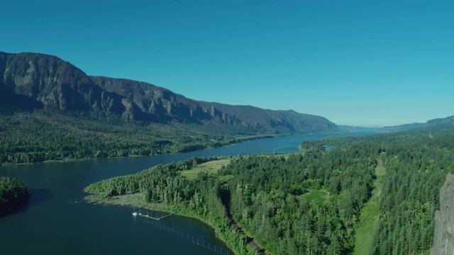 Aerial flyby moving right of Beacon Rock and the Columbia River on a blue sky sunny day