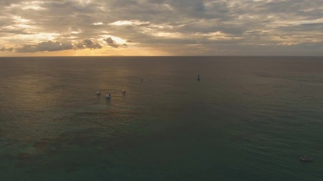 aerial footage sailboats with blue sails at sunset. Sailing yachts on sea surface sunset time.