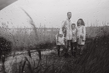 multiexposition. Beautiful family portrait dressed in raincoat near the lake