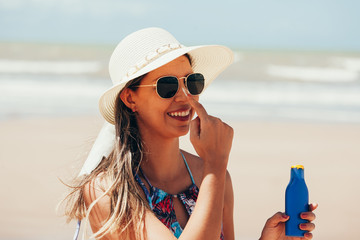 Sunscreen, sunblock. Woman putting solar cream on nose smiling beautiful summer day. Skincare. Girl...