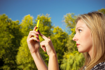 Woman sitting in park, using phone taking pictures