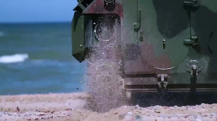 An army amphibious assault vehicle makes its way down a beach and into the ocean.