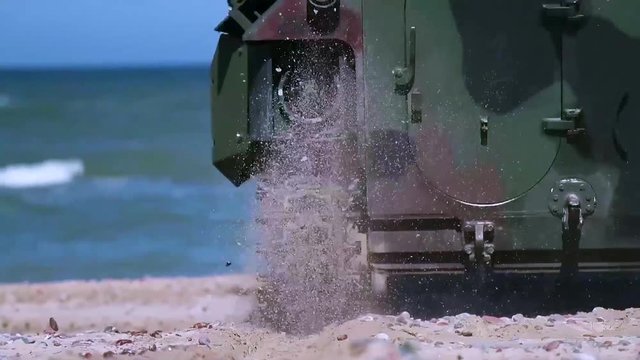 An army amphibious assault vehicle makes its way down a beach and into the ocean.