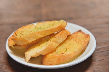 Plate with garlic bread on wooden table. Selective focus.
