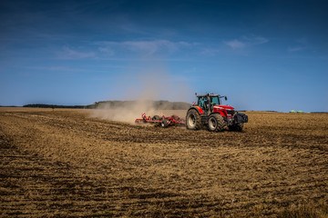 Fototapeta premium Roter Traktor auf Feld unter blauem Himmel - HDR