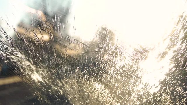 Fluid spraying on a windshield and wipers cleaning it off, in slow motion