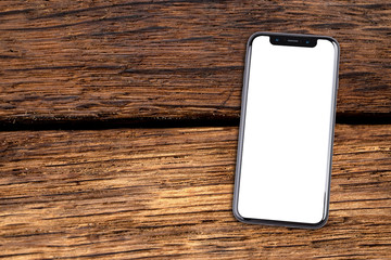 Smartphone lies on a wooden table. Isolated white screen with copy space.