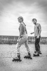 Friends learn rollerblading together have fun at park.