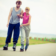 Young couple holding hands while rollerblading