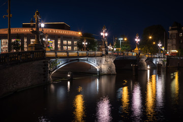 Fototapeta premium A bridge over the Amstel river and the lights reflected in the canal water , Amsterdam, the Netherlands.