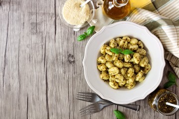 Gnocchi with pesto sauce. Top view table scene over wood with copy space.