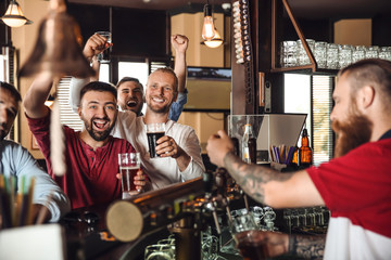 Fototapeta na wymiar Friends drinking beer at counter in bar