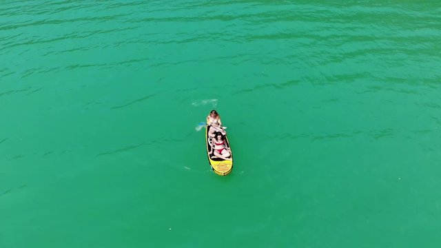vue a&eacute;rienne sur deux jeunes filles qui avancent sur un paddle gonflable en pagayant sur une eau verte 