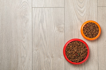 Bowls with food for cat and dog on wooden background. Pet care