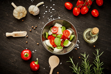 delicious salad with cherry tomatoes mozzarella and basil in a bowl on a black wooden table