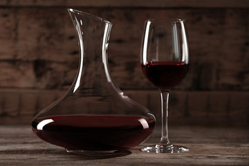 Elegant decanter and glass with red wine on wooden table